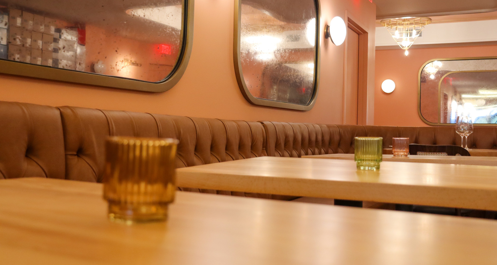 Tufted leather banquettes, rounded mirrors, and warm candlelight
